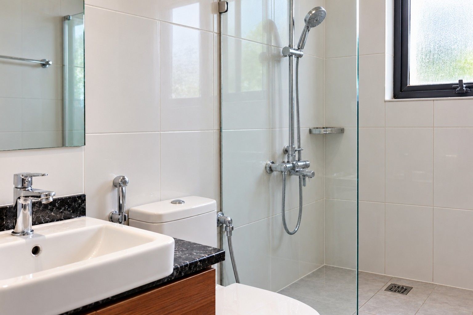 The same bathroom wall and fittings after deep cleaning, with bright tiles and shining chrome